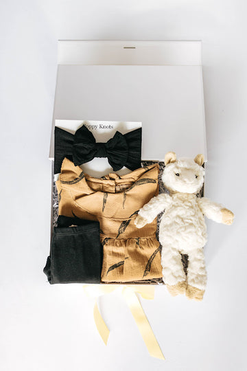 baby girl gift box with golden blouse, black leggings, black headband, and llama plushie