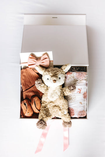 baby girl gift box with brick colored layette set and booties, pink bow, fawn lovey, and floral swaddle