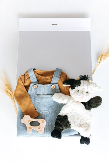 baby boy gift box with denim overalls, onesie, cow wood teether, and cow lovey