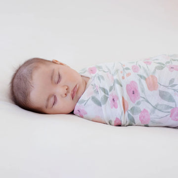 newborn baby wrapped in floral cotton muslin swaddle