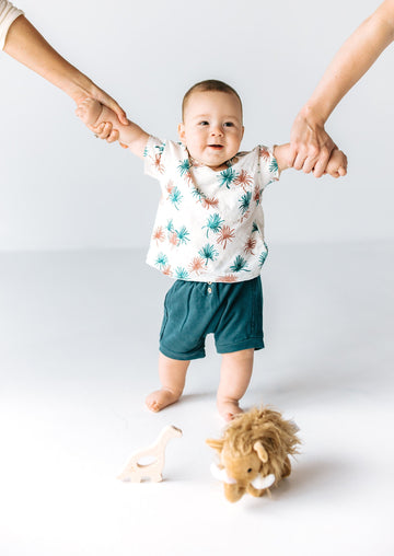 standing baby boy model with dinosaur wood teether and woolley mammoth plushie