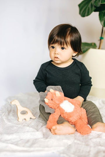 baby model holding orange dinosaur plushie