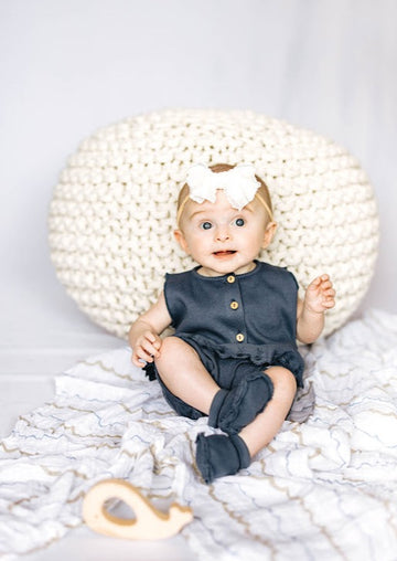 baby model sitting on blanket wearing a navy blue outfit and booties