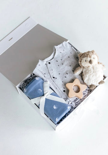 newborn boy gift box with blue swaddle, star teether, owl plushie, and onesie